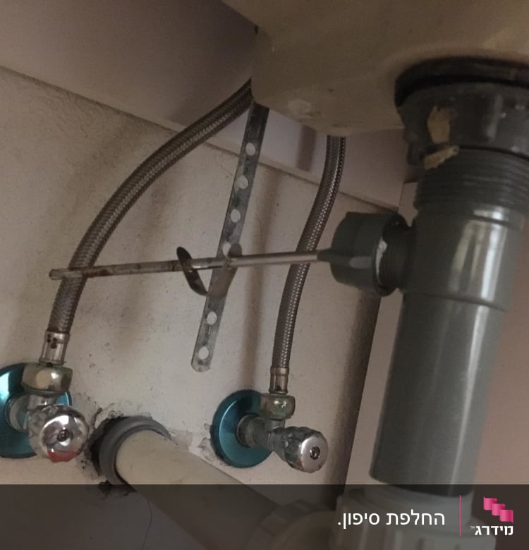 צינורות מתכת וברזים מתחת לכיור